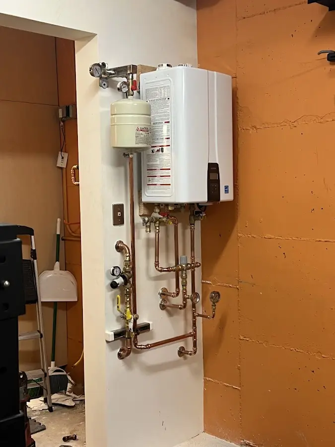 Plumbing technician inspecting water heater connections in Natick